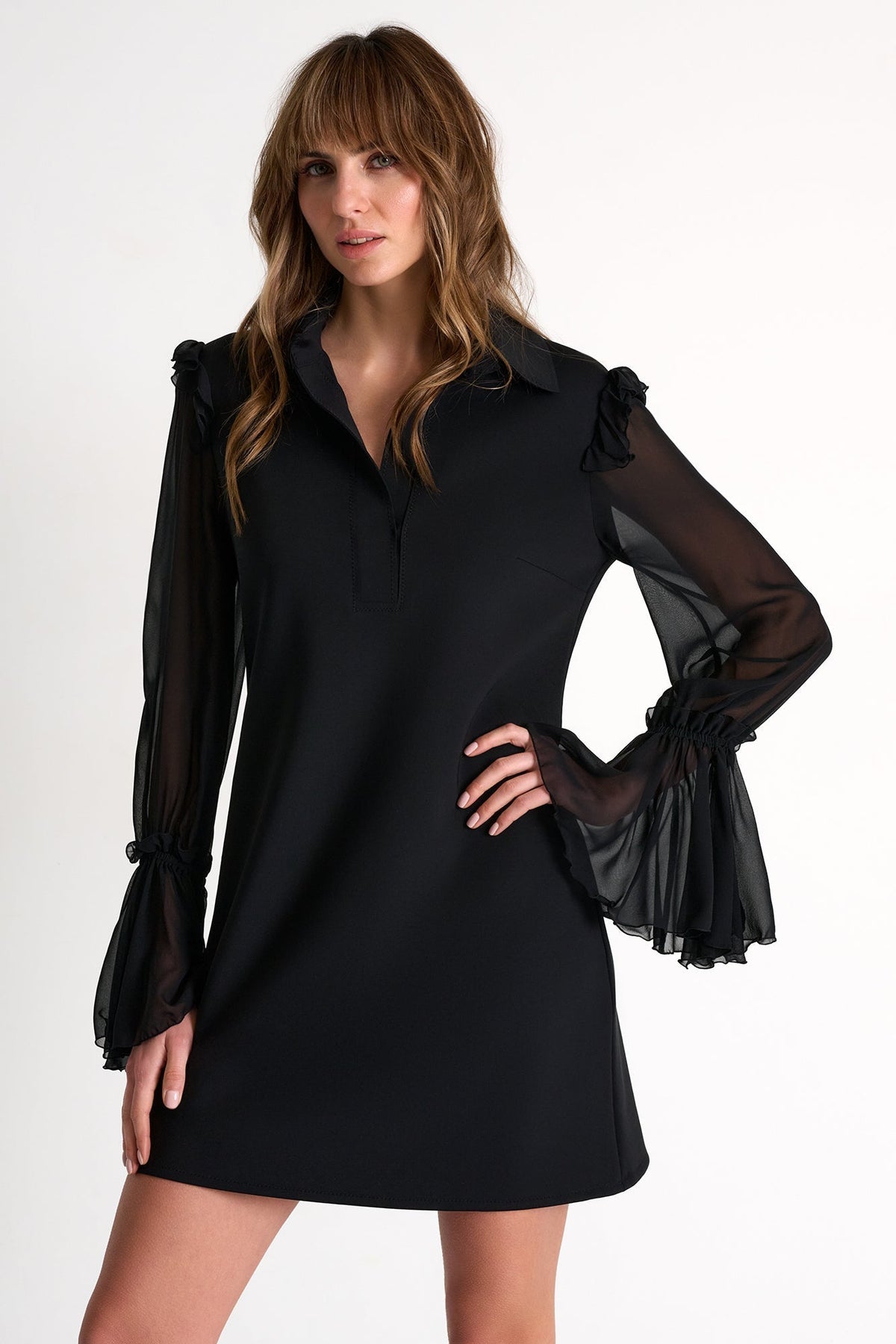 Woman wearing a black dress with sheer sleeves on a white background