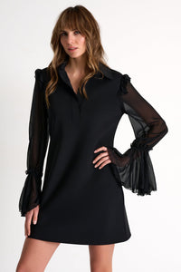 Woman wearing a black dress with sheer sleeves on a white background