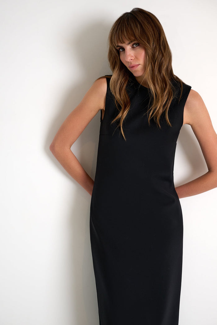 Woman wearing a black sleeveless dress against a white background