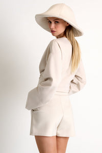 Woman wearing a beige outfit with a matching hat on a white background