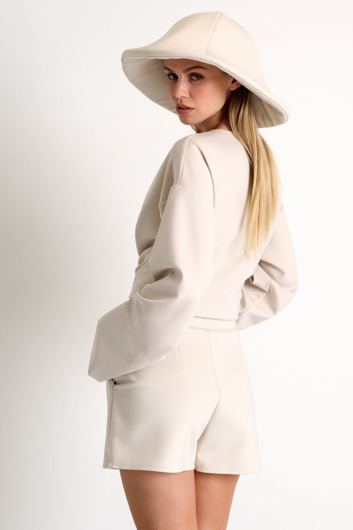 Woman wearing a beige outfit with a matching hat on a white background