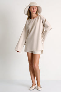 Woman wearing a beige dress and hat on a white background