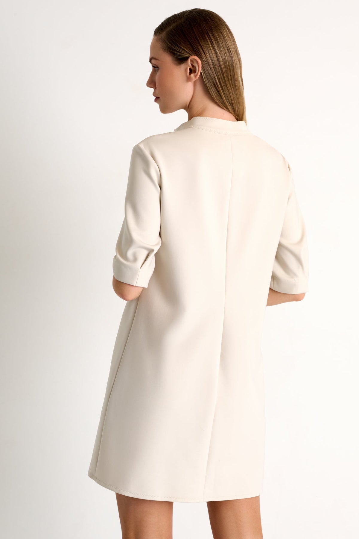 Woman wearing a beige dress against a plain background