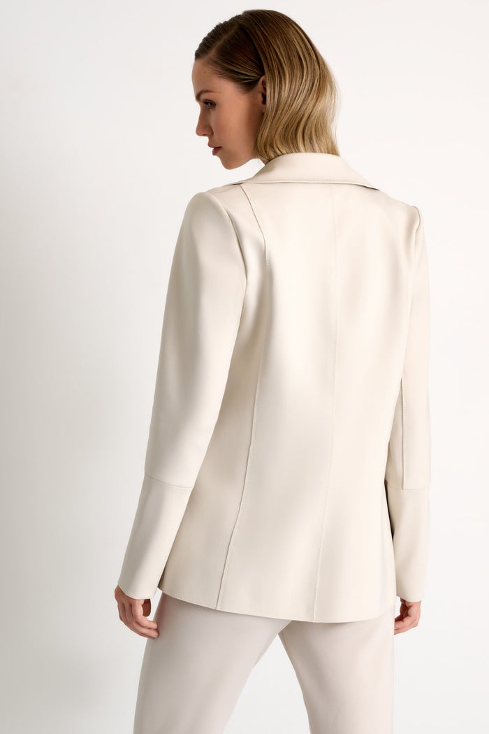 Woman wearing a light beige blazer on a plain background