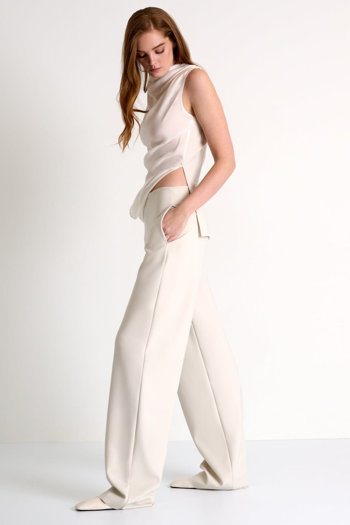 Woman wearing a cream-colored outfit with wide-leg pants on a white background