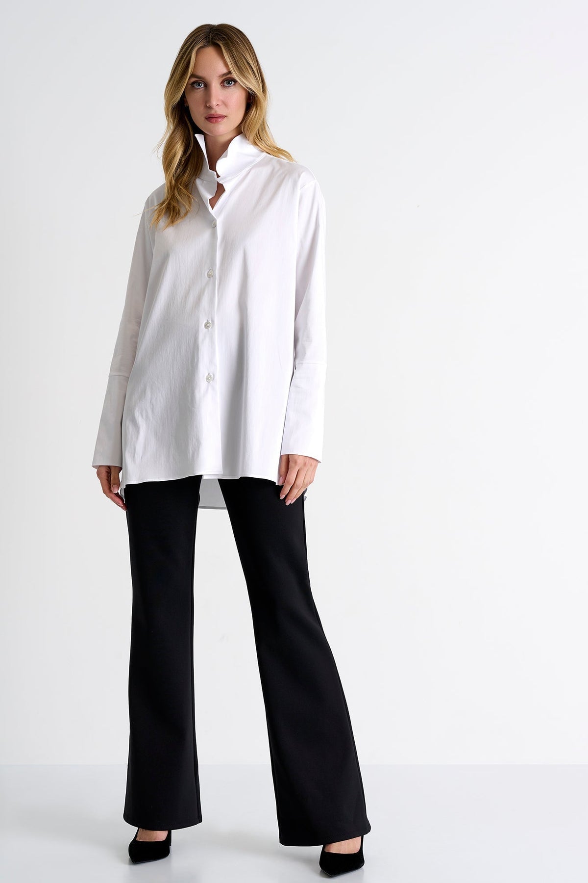 Woman wearing a white blouse and black pants on a white background