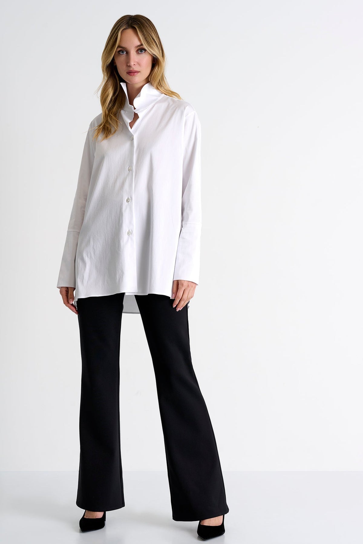 Woman wearing a white blouse and black pants on a white background
