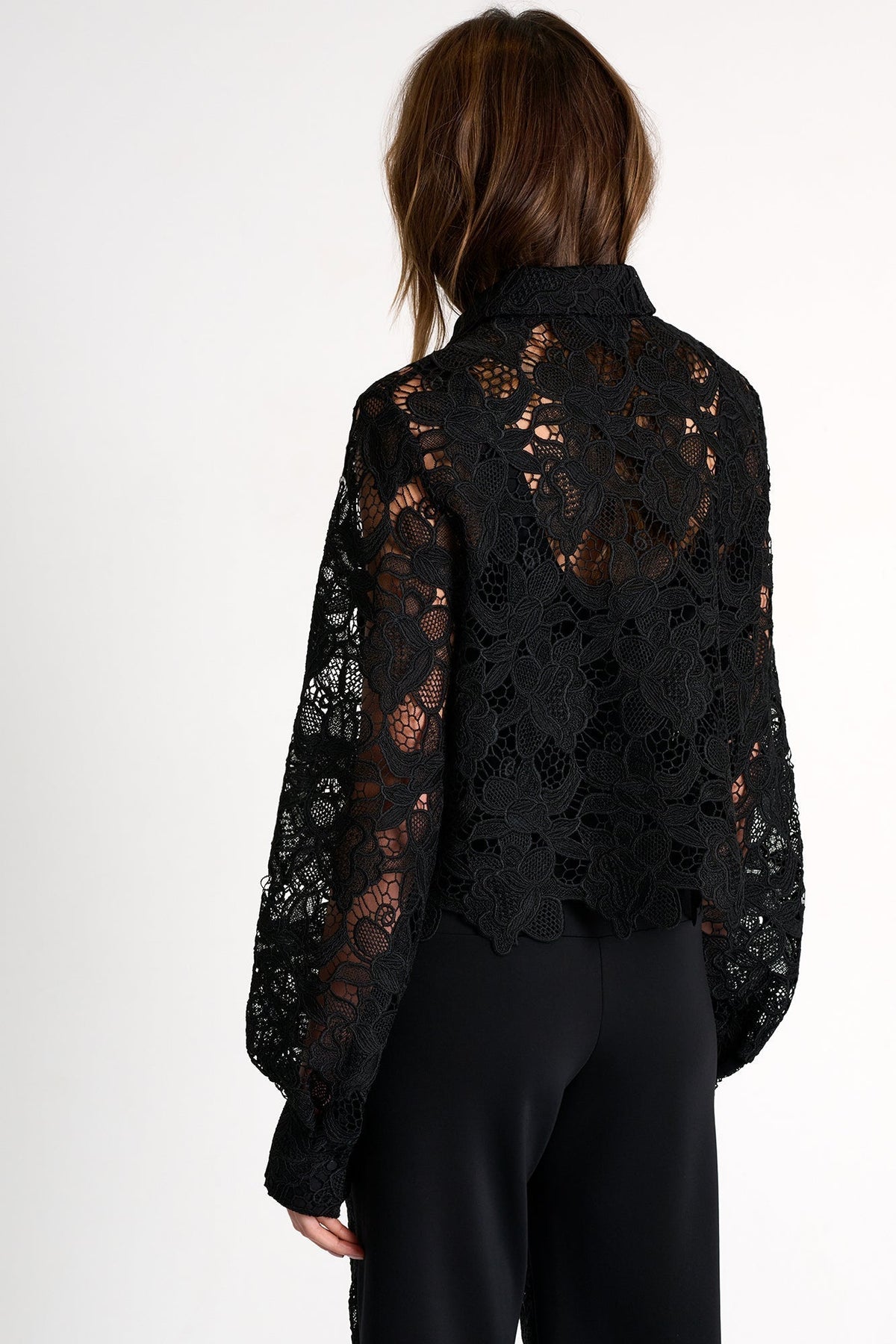 Black lace top worn by a person on a white background