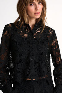 Woman wearing a black lace top against a white background