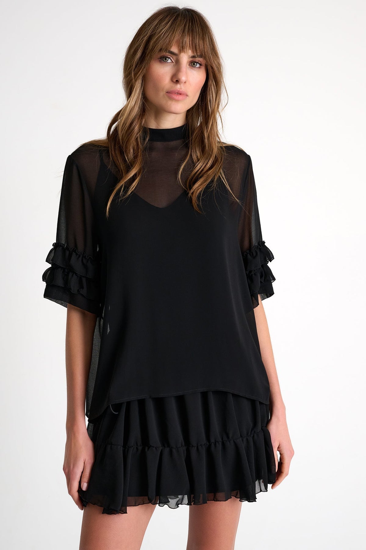 Woman wearing a black dress with sheer sleeves on a white background