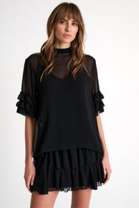 Woman wearing a black dress with sheer sleeves on a white background