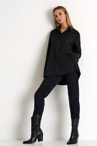Woman wearing a black outfit with a shirt, leggings, and black boots on a white background