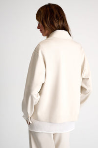 Person wearing a cream-colored jacket on a white background