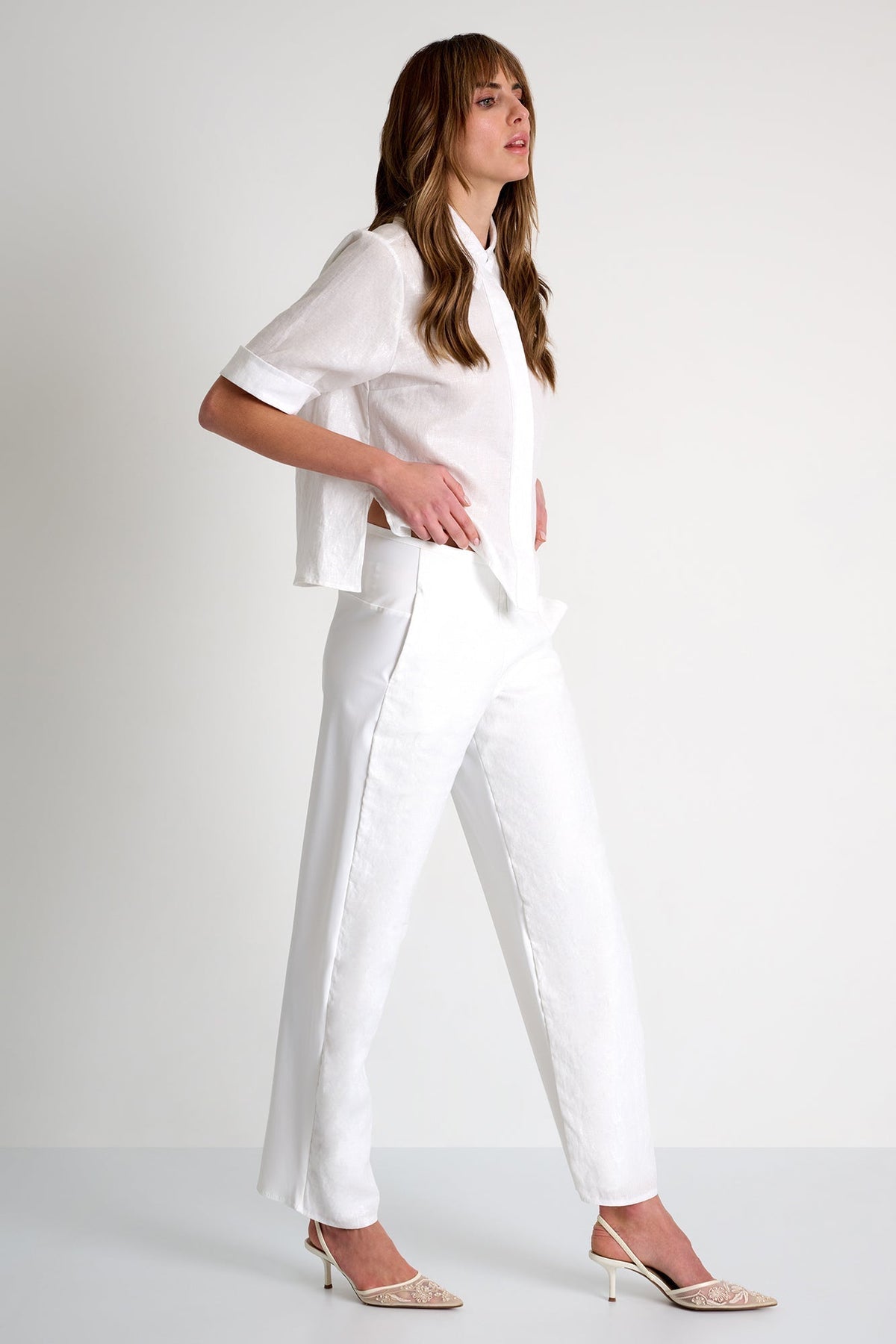 Woman wearing a white outfit on a plain background