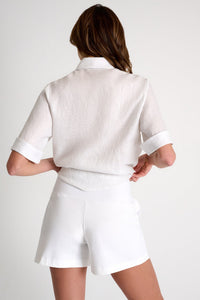 Person wearing a white outfit with a jacket and shorts on a plain background
