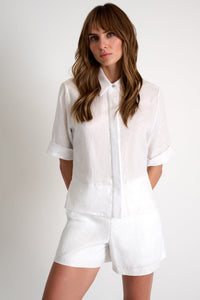 Woman wearing a white shirt and shorts on a plain background