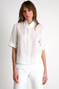 Woman wearing a white blouse and pants on a plain background