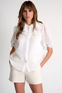 Woman wearing a white blouse and shorts on a plain background