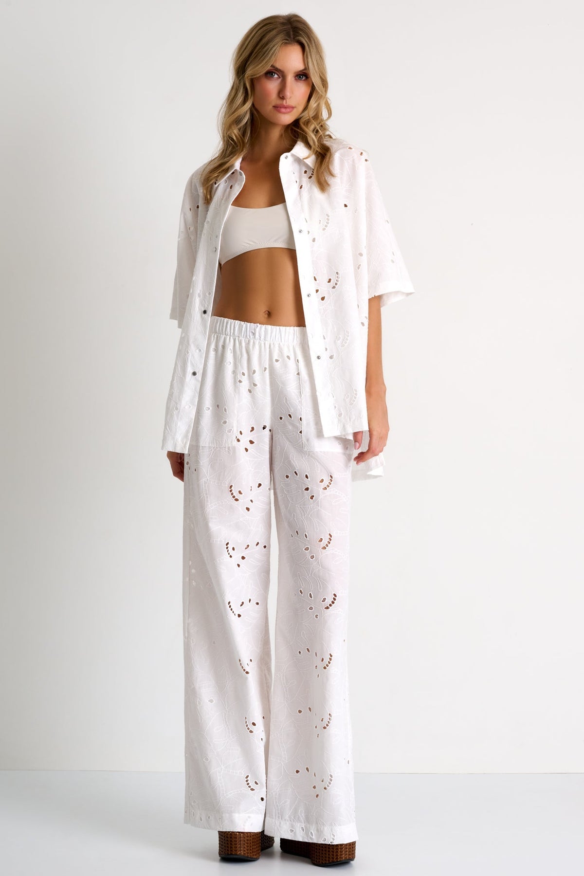 Woman wearing a white outfit with heart patterns on a plain background