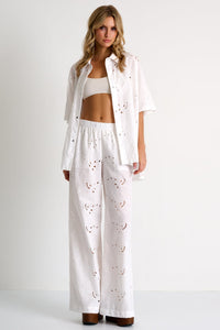 Woman wearing a white outfit with heart patterns on a plain background